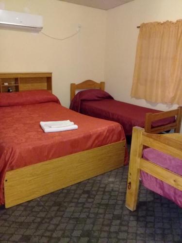 a hotel room with two beds and a chair at Cabaña Jofra in San Rafael