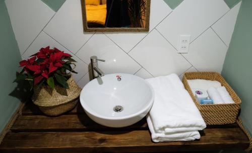 a bathroom with a sink and a vase with red flowers at The Kadupul Homecation in Da Lat