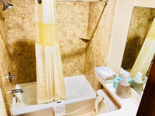 a bathroom with a shower and a toilet and a sink at Sunset Inn Longview in Longview