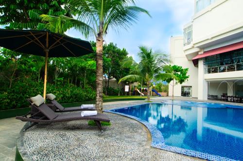 a chair with an umbrella next to a swimming pool at Swiss-Belhotel Lampung in Bandar Lampung