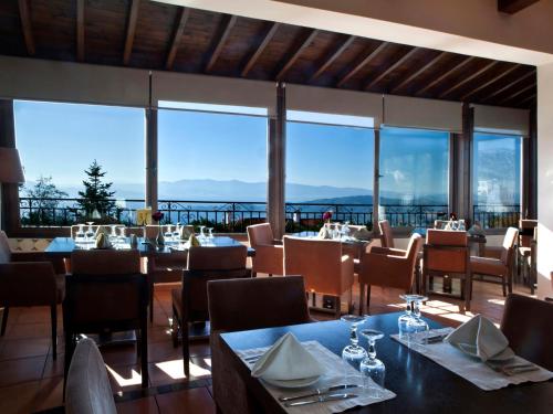 a restaurant with tables and chairs and large windows at Portaria Hotel in Portariá