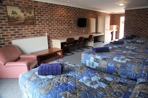 a room with four beds and a table and chairs at Big Trout Motel in Oberon