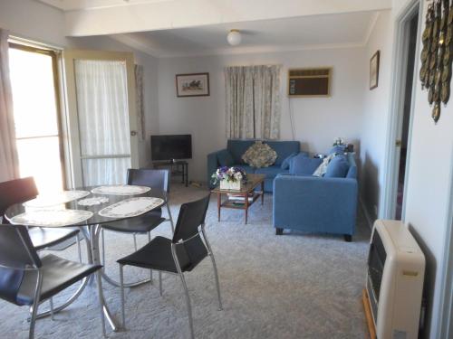 a living room with a blue couch and tables and chairs at Glenfield Cottage in Yarck