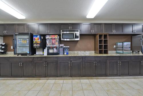 a large kitchen with two refrigerators and microwaves at Americas Best Value Inn and Suites Bismarck in Bismarck