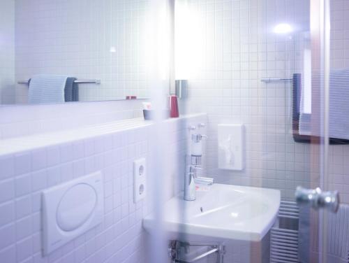 ein weißes Badezimmer mit einem Waschbecken und einem Spiegel in der Unterkunft Tagungshaus Himmelspforten - Self Check-In in Würzburg