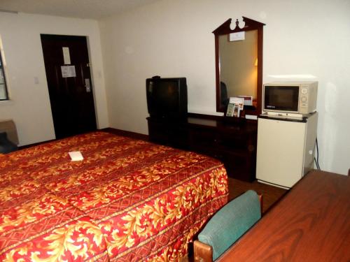 a hotel room with a bed and a television at Budgetel Inn Houston/Nasa in Webster