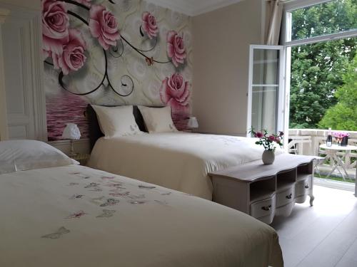 two beds in a bedroom with roses on the wall at La Demeure d'Elodie in Épernay