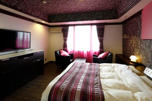 a hotel room with a bed and a flat screen tv at Hotel Sunset (Adult Only) in Choshi
