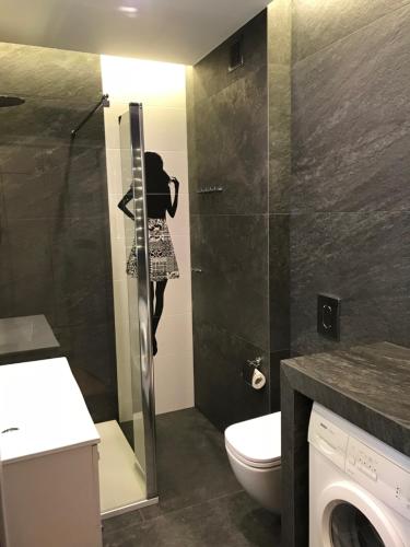 a bathroom with a toilet and a shower with a picture of a woman at Sopot Apartment in Sopot