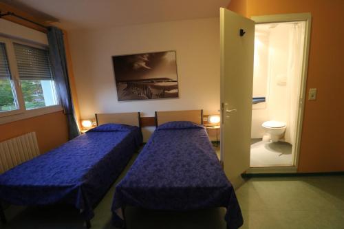 ディジョンにあるETHIC ETAPES DIJON Accueil 24h24 et parking gratuitのベッド2台とバスルームへのドアが備わる客室です。
