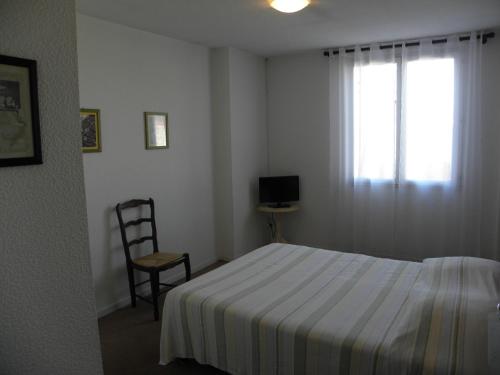 a bedroom with a bed and a chair and a window at Le Barry in Villefranche-dʼAlbigeois