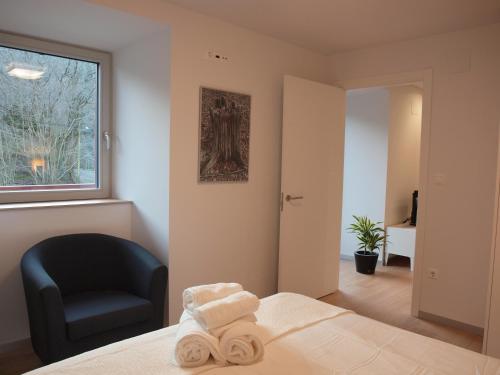 a bedroom with a bed and a chair and a window at Mendialdea Amaiur Baztán in Maya del Baztán