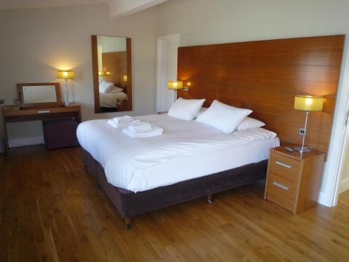 um quarto com uma grande cama branca e uma cabeceira em madeira em Castlemartyr Holiday Lodges 2 Bed em Castlemartyr