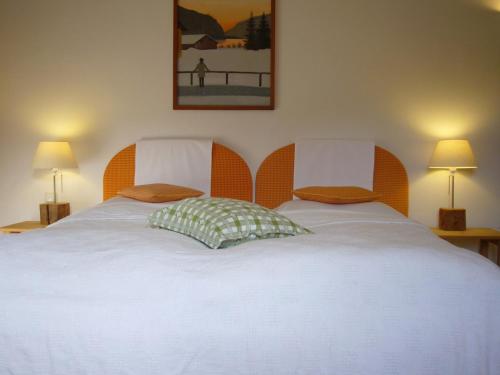 a bedroom with a large white bed with two pillows at Sonnwirtstöckl am See in Sankt Gilgen