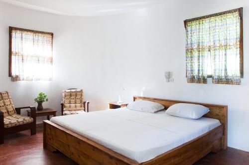 - une chambre avec un grand lit et une chaise dans l'établissement Auberge de Grand Popo, à Grand-Popo