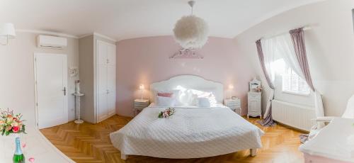 a bedroom with a white bed with flowers on it at Aurora Vendégház in Hévíz