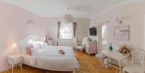 a white bedroom with a bed and a living room at Aurora Vendégház in Hévíz