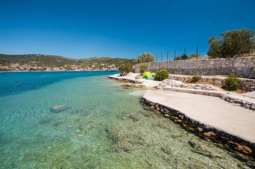 a beach with clear blue water and a stone wall at Villa Nada in Vinišće