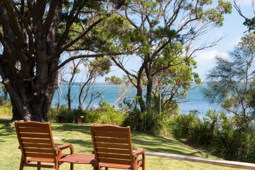 two chairs sitting on the grass near the water at By the Beach B&B Self Contained Apartments in Sanctuary Point