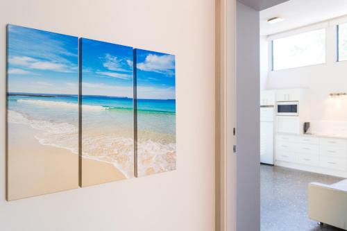 a room with four paintings of the beach at By the Beach B&B Self Contained Apartments in Sanctuary Point