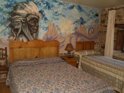 1 dormitorio con 2 camas y un mural en Hostal Tribal en Puebla de Sanabria