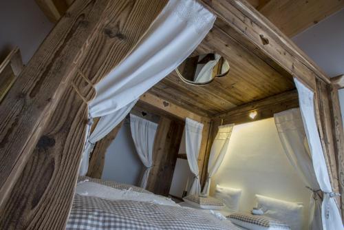 a bedroom with a canopy bed with white curtains at Berry House in Vigolo Vattaro