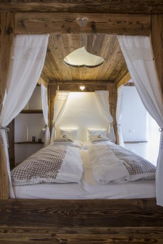 a bedroom with a white bed with a wooden ceiling at Berry House in Vigolo Vattaro