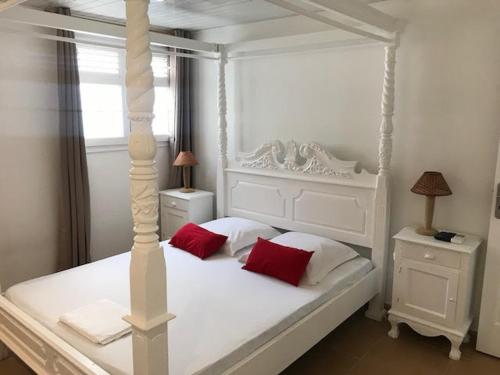 a bedroom with a white bed with red pillows at Gite Grenadille Martinique piscine privée, in Sainte-Luce