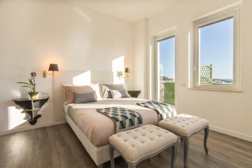 a white bedroom with a large bed with a window at Eleventh Floor Suites in Cagliari