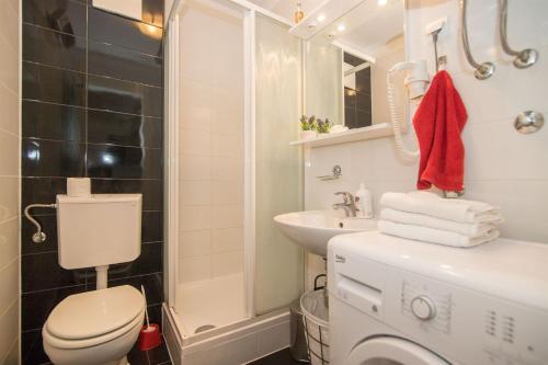 a bathroom with a toilet and a sink and a washing machine at Apartment Matmar in Split