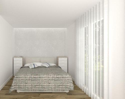 um quarto branco com uma cama e uma janela em Piccolo Moderno Appartamento sulla Spiaggia in Centro em Lido di Jesolo