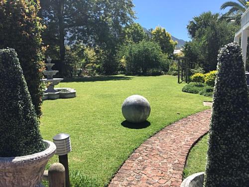 a garden with a large stone ball on the grass at Oude Berg Guesthouse - 10 Caledon Street in George