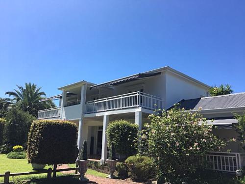 a large white house with bushes and trees at Oude Berg Guesthouse - 10 Caledon Street in George