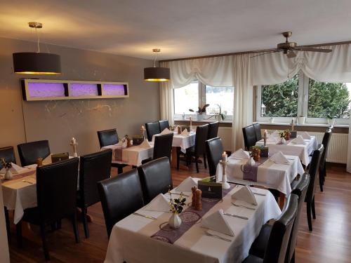 a restaurant with tables and chairs with white tablecloths at Hotel Zur Fichtenbreite -Garni- in Coswig