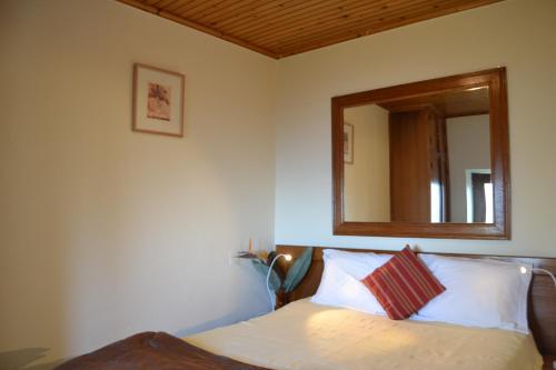 een slaapkamer met een bed met een spiegel aan de muur bij Casal São João Cottages 105 in Fajã da Ovelha
