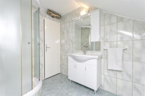 a white bathroom with a sink and a shower at Apartments Toni in Vodice