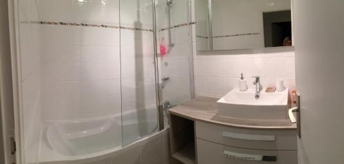 a white bathroom with a sink and a shower at Appartement, vue mer à 150m de la plage in Trouville-sur-Mer
