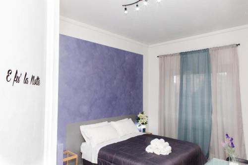 a bedroom with purple walls and a bed with white pillows at Foresteria Boccadasse in Genova