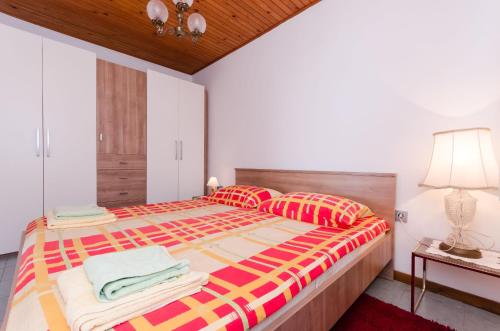 a bedroom with a large bed with colorful sheets and pillows at Apartments Ilinka in Lovran