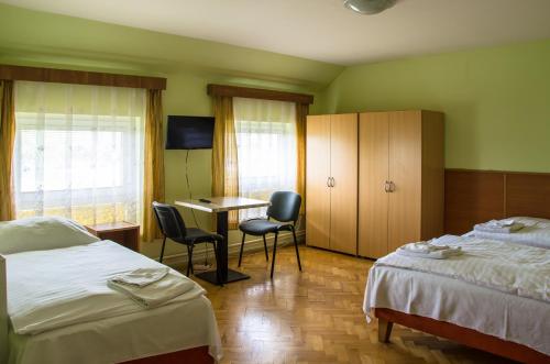 a hotel room with two beds and a table and chairs at Hotel U Jezera in Velký Osek