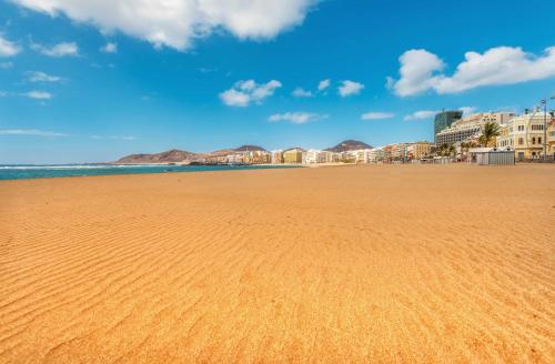 a sandy beach with buildings and the ocean at Maresía Canteras Urban Hotel in Las Palmas de Gran Canaria
