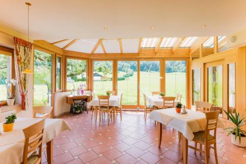 a conservatory with tables and chairs and windows at Pension Anna in Mondsee