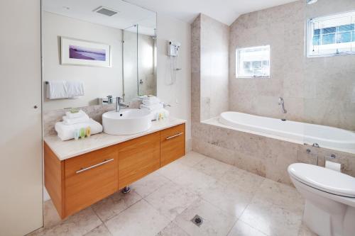 a bathroom with a sink and a tub and a toilet at Seashells Mandurah in Mandurah