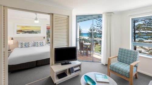 a bedroom with a bed and a tv and a chair at Oaks Gold Coast Calypso Plaza Suites in Gold Coast