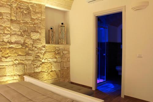 ein Schlafzimmer mit einer Steinmauer, einem Bett und einem Eingang in der Unterkunft DeShome Guest House in Bari