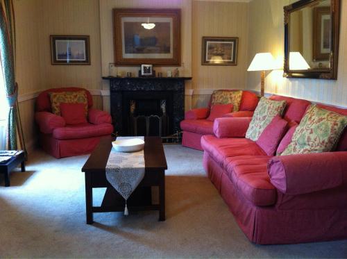 sala de estar con 2 sofás rojos y chimenea en Carlingford House Town House Accommodation A91 TY06 en Carlingford