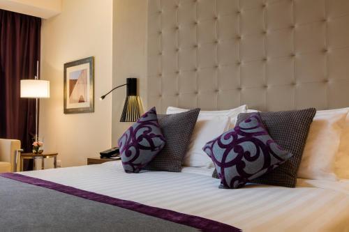 a bedroom with a large bed with purple and white pillows at Somewhere Hotel Al Ahsa in Al Hofuf