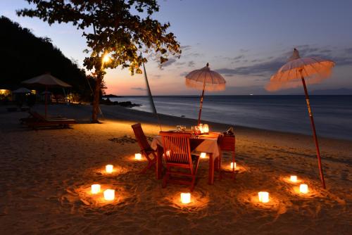 a table with candles and umbrellas on the beach at Cocotinos Sekotong Lombok in Sekotong