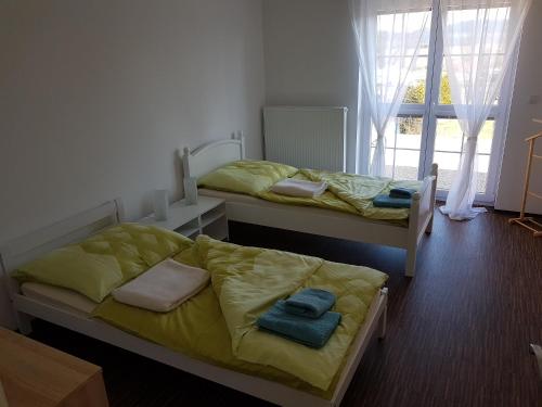 2 camas en una habitación con sábanas amarillas y toallas en Apartmán Sadová 430, en Chodová Planá