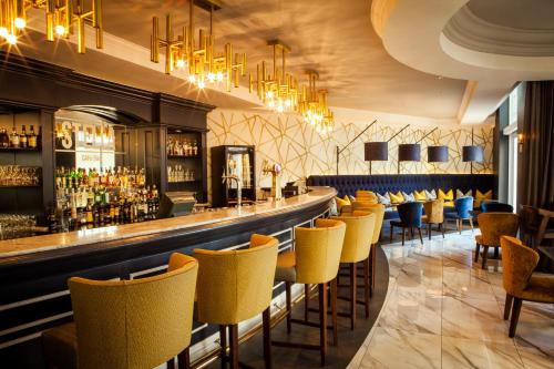 a bar with yellow chairs and a long counter at Southern Sun The Cullinan in Cape Town